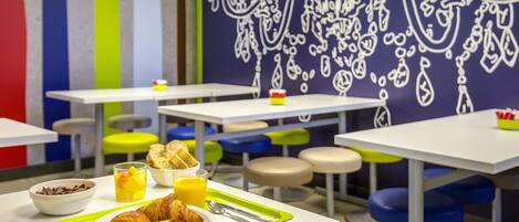 Un comedor con mesas y sillas, una bandeja con comida y bebidas, y una pared con un diseño decorativo.