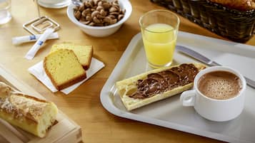 A breakfast tray with croissants, chocolate spread, a glass of orange juice, a cup of coffee, and a loaf of bread.