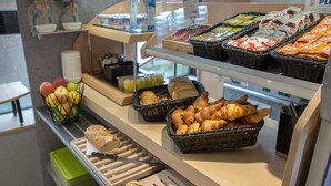 Un bufé de desayuno con pan, bollería y fruta.