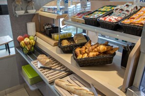Un bufé de desayuno con pan, bollería y fruta.
