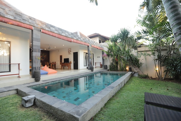 A modern house with a swimming pool, a patio area, and a well-maintained garden.
