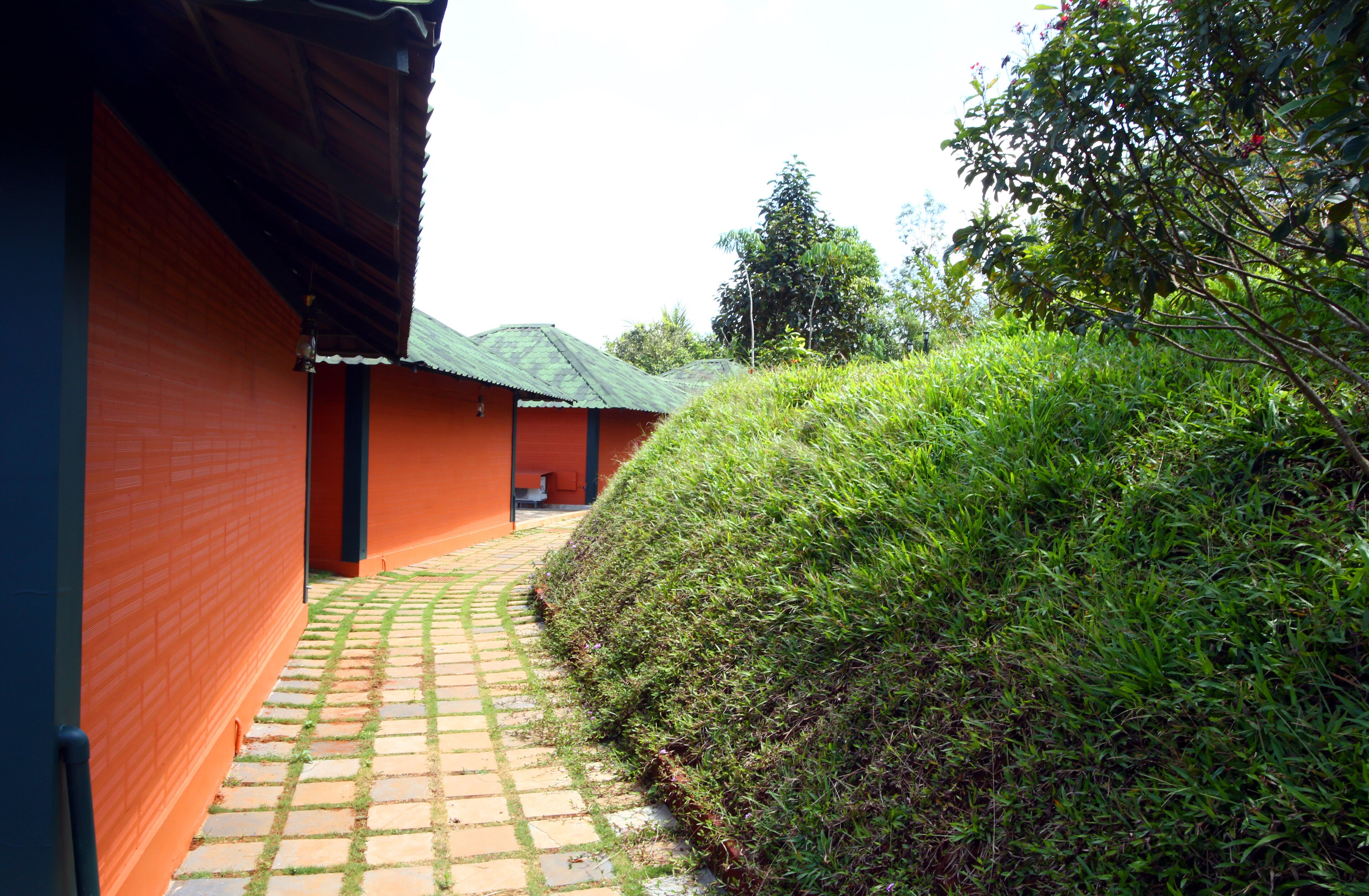 Un camino que lleva a un edificio de fachada roja y tejado verde.