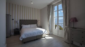 A bedroom with a bed, bedside tables, a dresser, a window with curtains, and a view of the outdoors. - Park Hotel Italia (Cannero Riviera)