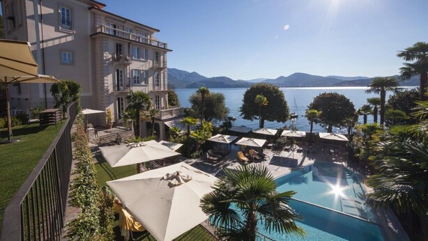 A hotel with a pool, outdoor seating, and a view of the lake. - Park Hotel Italia (Cannero Riviera)