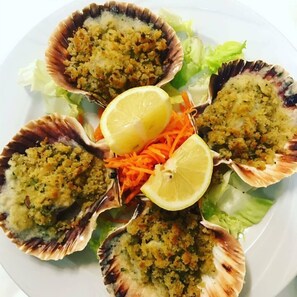 A plate of scallops topped with breadcrumbs and garnished with lemon slices and shredded carrots. - Hotel Ristorante Gallo D'Oro (Savignano sul Panaro)