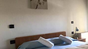 Una camera da letto con una testiera in legno, un letto con biancheria azzurra e bianca, un comodino con un telefono e una lampada a muro.