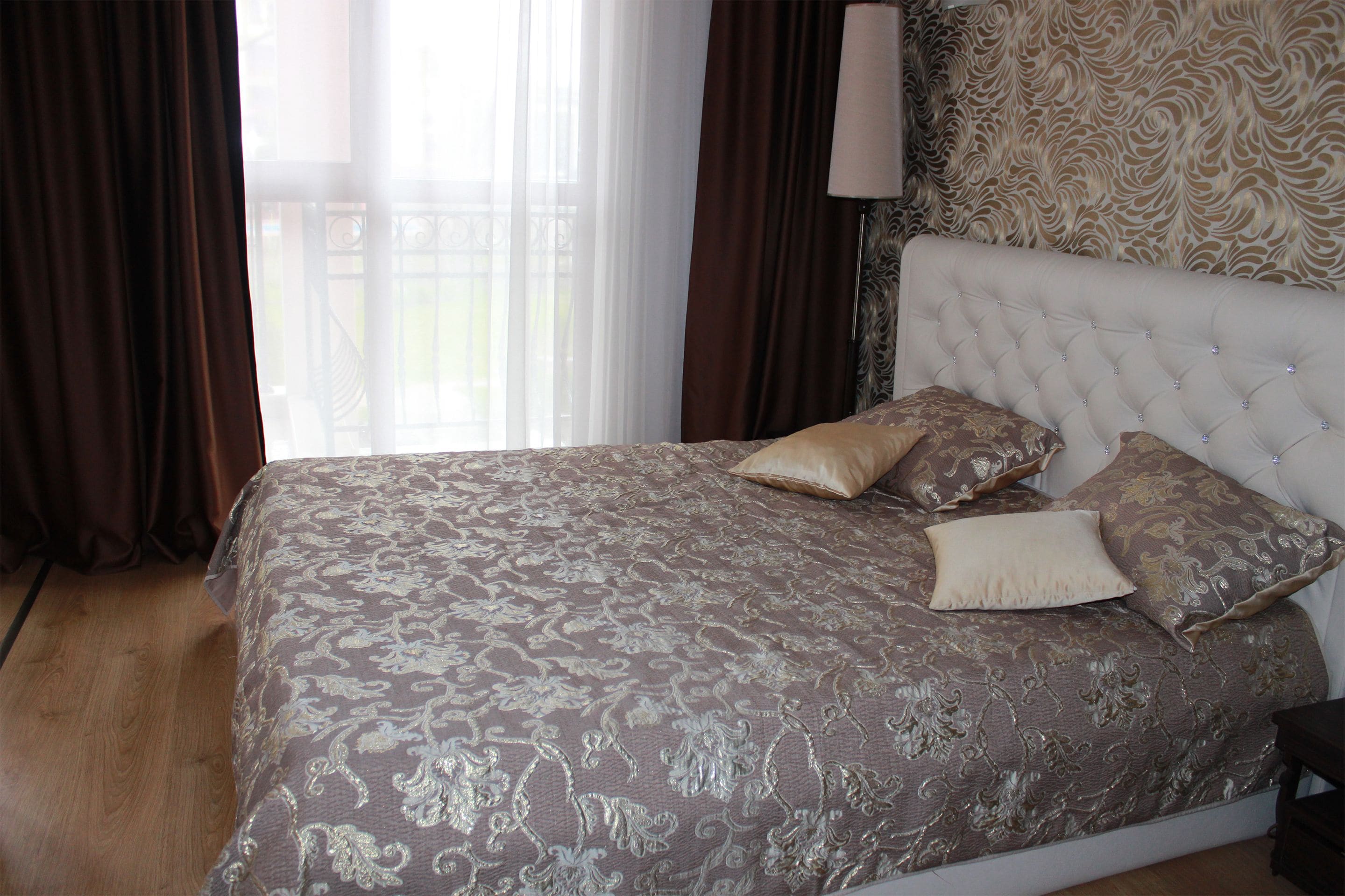 Un dormitorio con una cama grande, cabecera y ventana con cortinas.