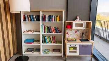 A room with a bookshelf, a desk with a sink, and a lamp.