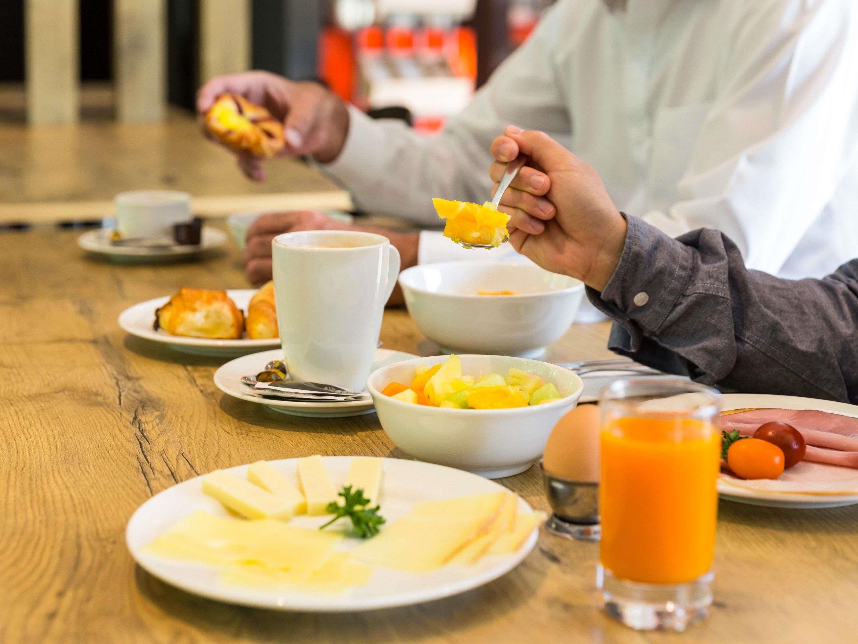 A breakfast setting with plates of food, a coffee cup, and a glass of orange juice.