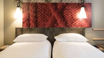 A hotel room with two beds, a marble wall, and pendant lights.