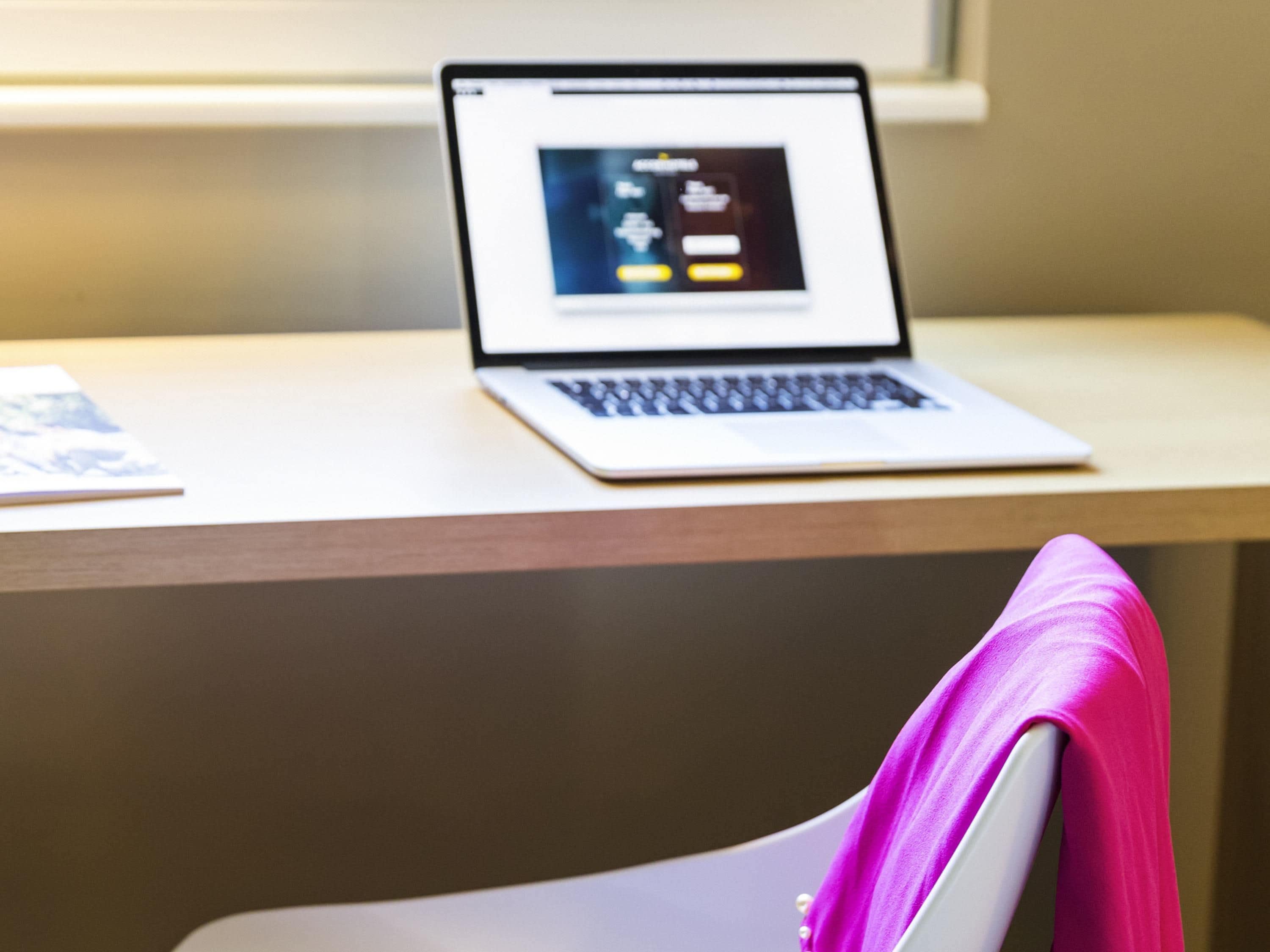 Un ordinateur portable sur un bureau, avec une fenêtre en arrière-plan.