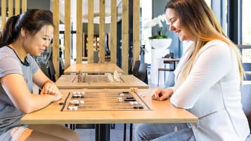 Dos personas jugando un juego de mesa en una mesa de madera en un ambiente interior moderno.