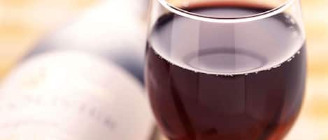 Una botella de vino y una copa de vino tinto.