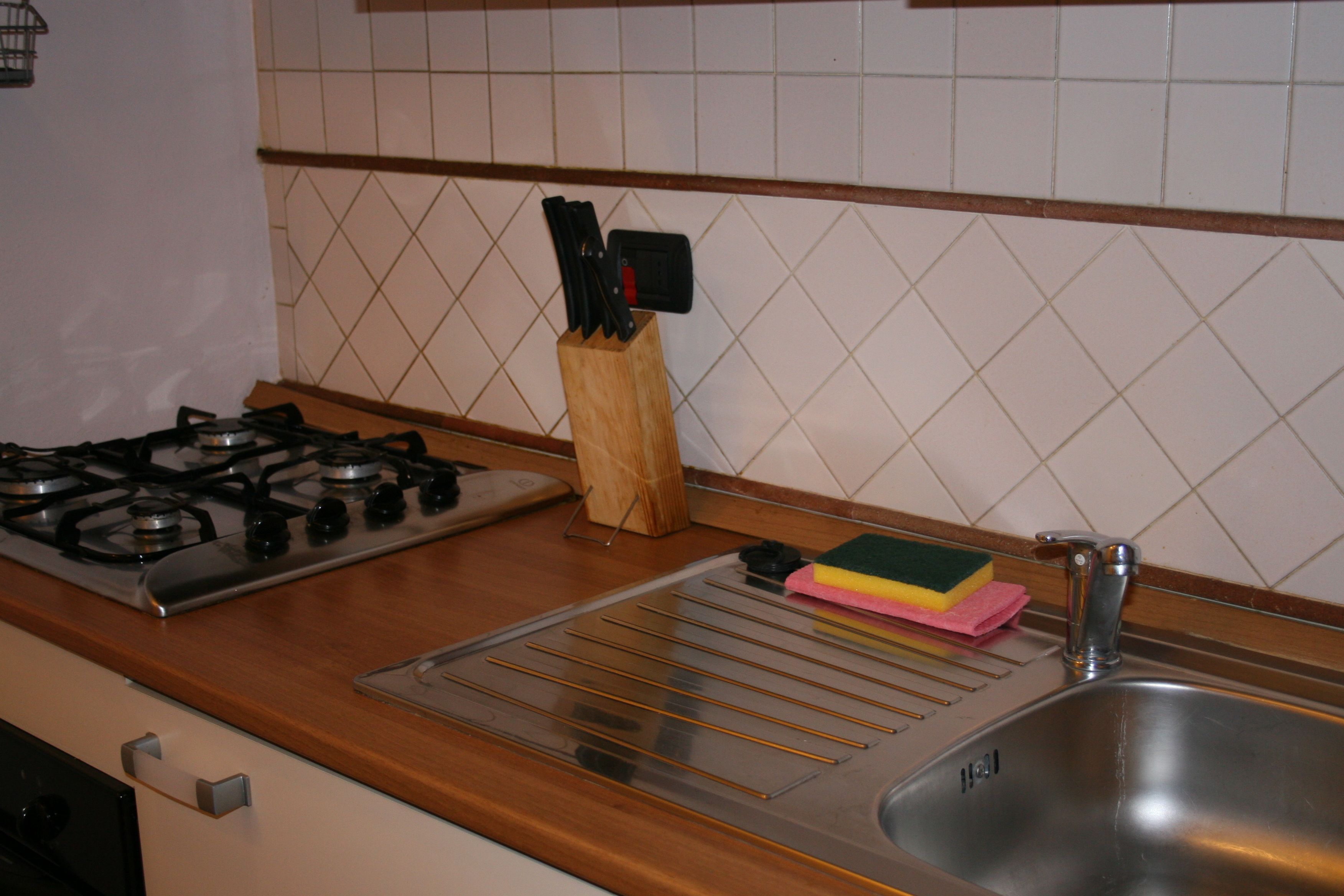 A kitchen with a gas stove, a sink, and a knife block.