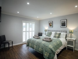 A bedroom with a bed, a chair, a bedside table, and a window with blinds.