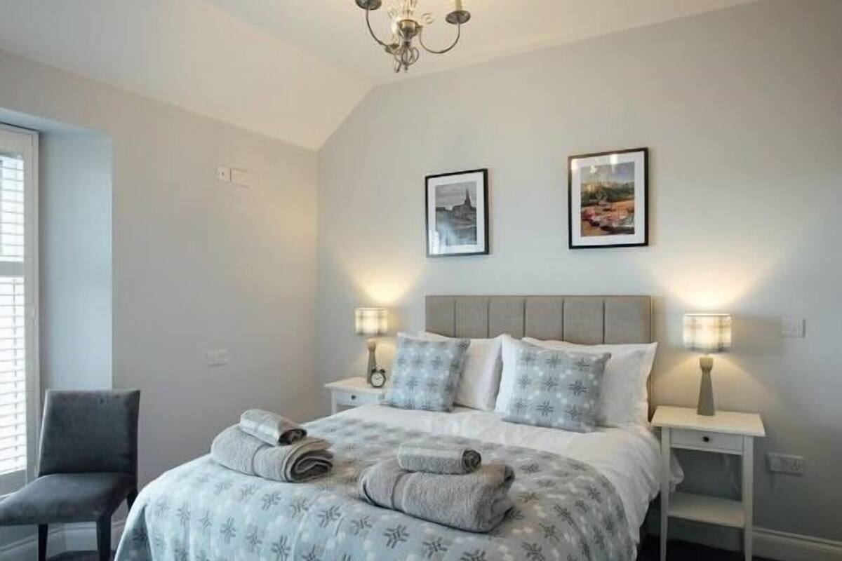 Une chambre à coucher avec un lit, deux tables de chevet, une chaise et un lustre.
