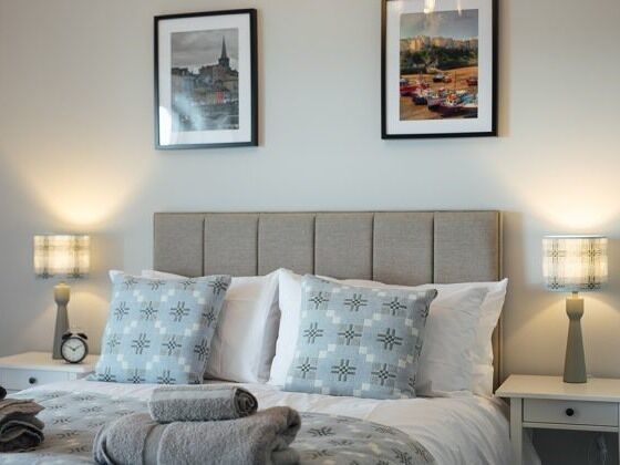A neatly made bed with patterned pillows, a headboard, and two bedside lamps.