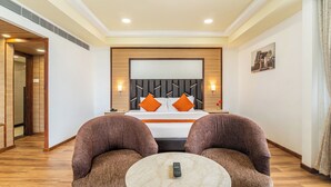 A hotel room with a large bed, two armchairs, a small round table, and a nightstand. - Sterling V Grand Madurai (Madurai)