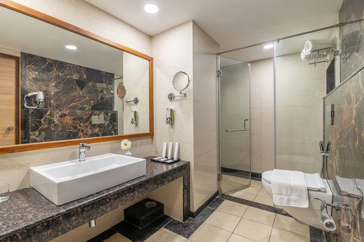A modern bathroom with a large sink, mirror, and shower.