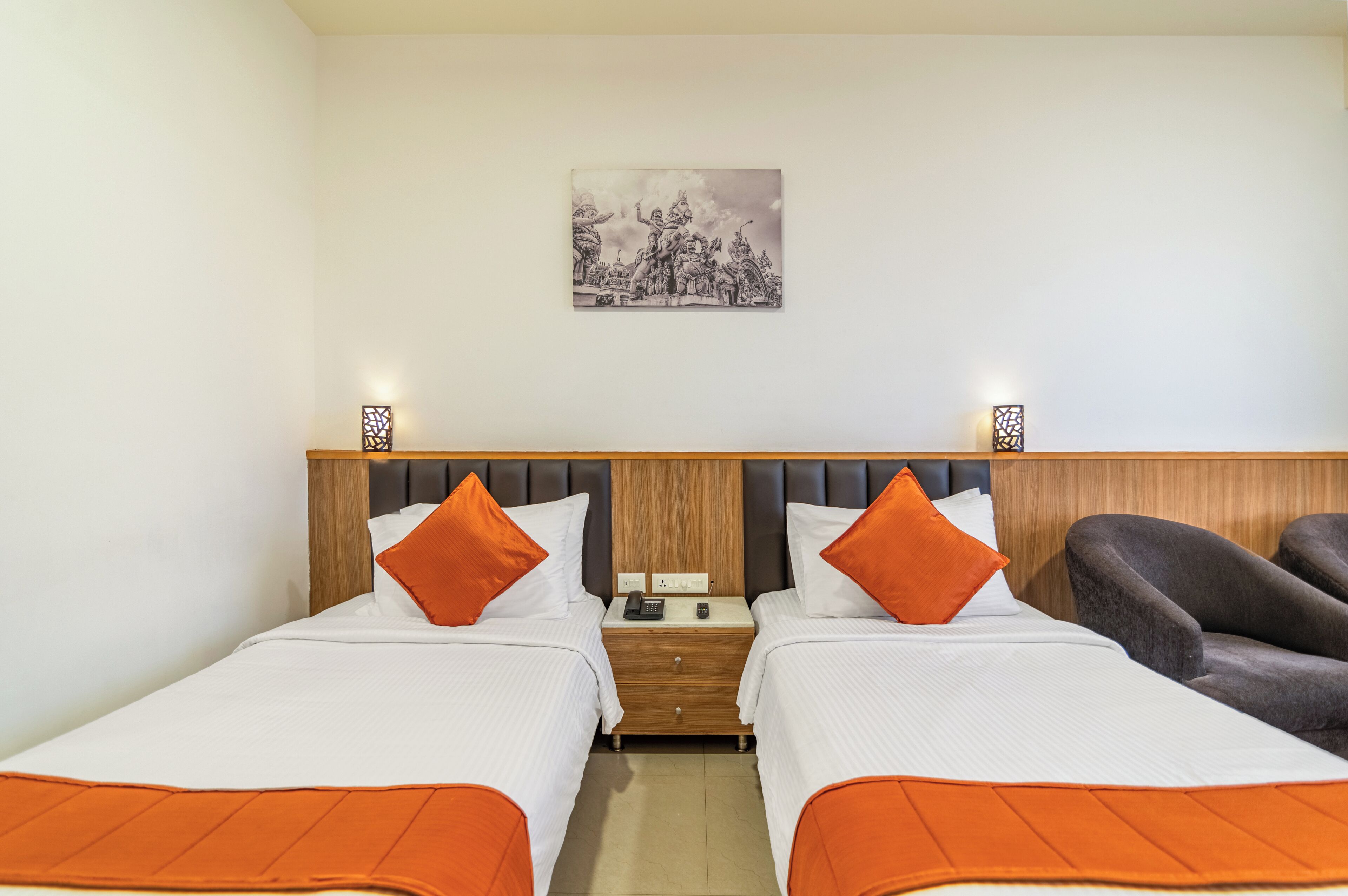 Een hotelkamer met twee bedden, een nachtkastje, een telefoon en een stoel.