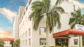 A modern hotel with a sign reading "Sterling Grand Madurai." It features a white facade, palm trees, and a red awning. - Sterling V Grand Madurai (Madurai)