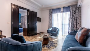 Una sala de estar moderna con un sofá azul, una mesa de centro de vidrio y una alfombra estampada.