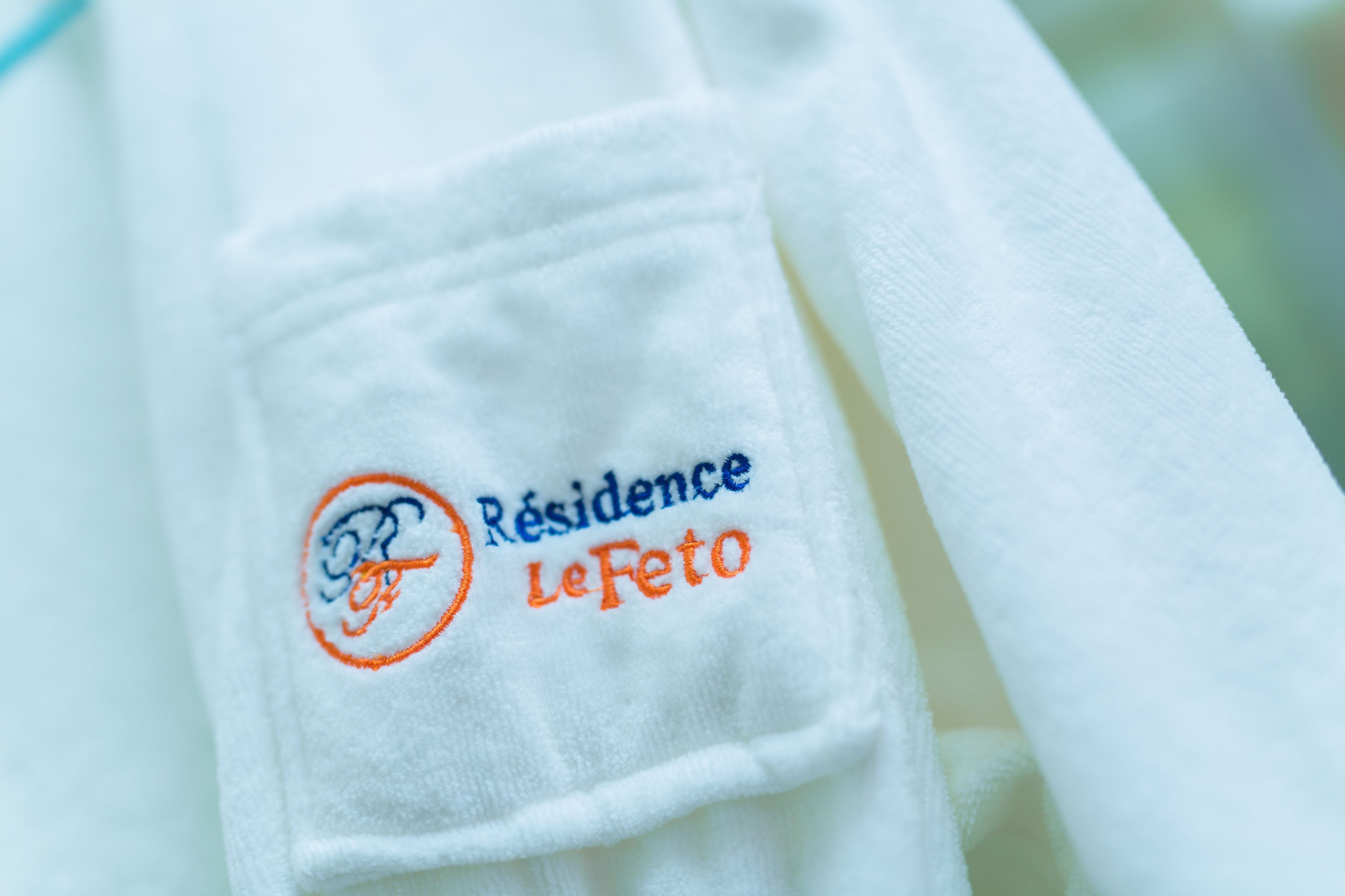 Uma toalha branca com bordado de texto e um logotipo.
