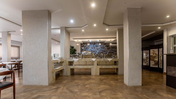 Un amplio vestíbulo de hotel con una zona de estar central, paredes con baldosas y un diseño moderno.