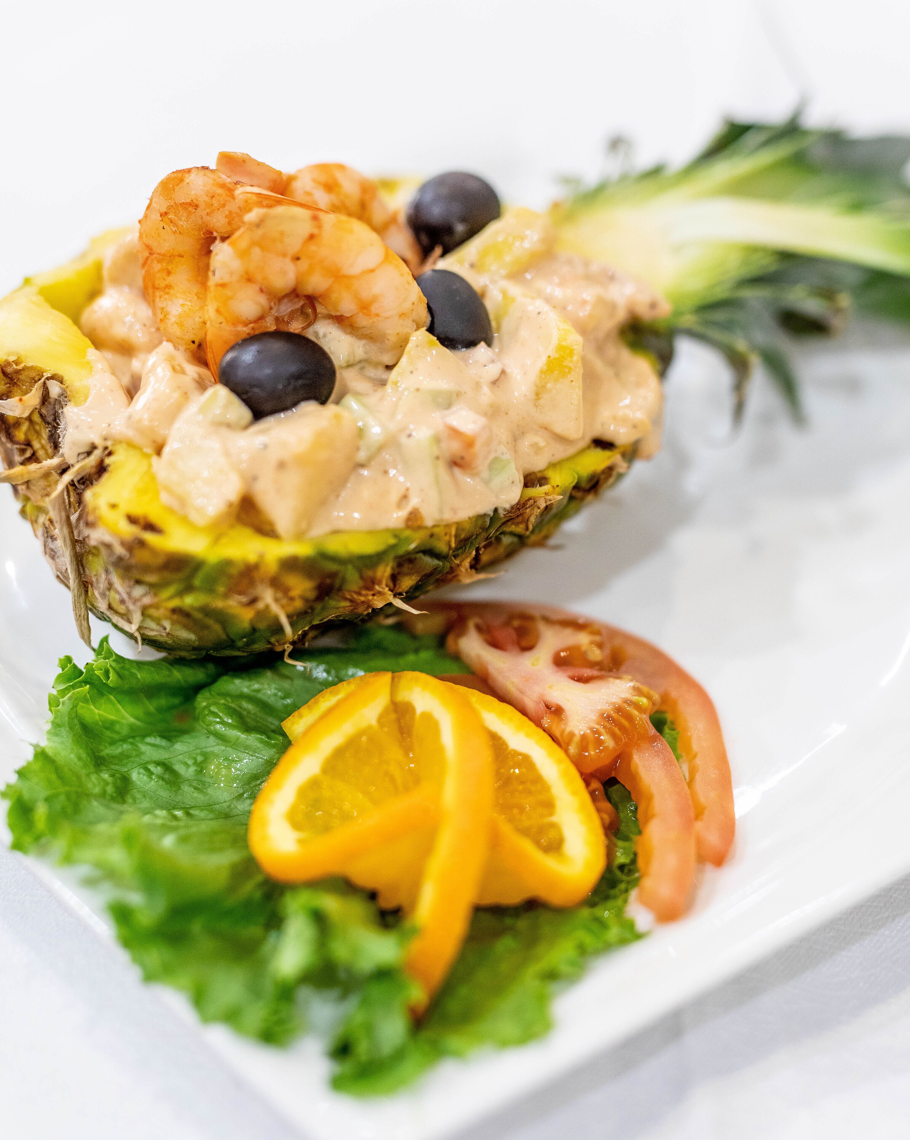 A salad with shrimp, olives, and a creamy dressing on a bed of lettuce.