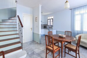 Eine moderne Küche mit weißen Schränken, einem Esstisch mit Stühlen und einer Treppe mit Holzwangen.