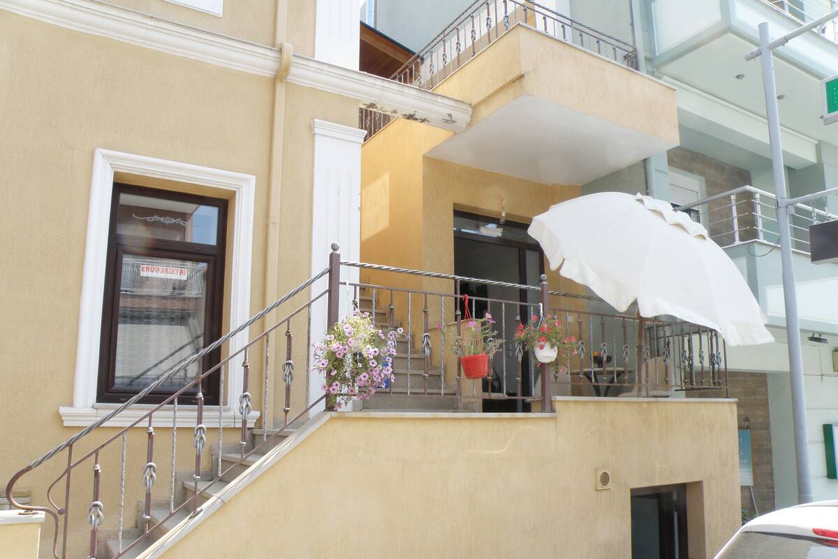 Un bâtiment doté d’un balcon, d’un escalier et d’un parasol blanc.