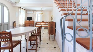 Un comedor espacioso con una mesa redonda grande, sillas de madera y una escalera con barandillas de metal.