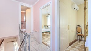 Un pasillo con una escalera que conduce a un dormitorio con piso a cuadros y una cama.