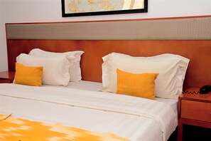 A neatly made bed with white and yellow pillows, a wooden headboard, and a bedside table with a telephone. - Résidence Feto III (Dakar)