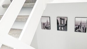 A staircase with white railings leading to a room with three black-and-white cityscape photographs on the wall. - Outfield Homes (Peterborough)