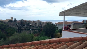 Vista de un pueblo costero con edificios históricos, una estructura similar a un castillo y cielo despejado.