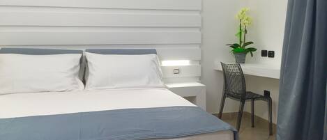 A modern hotel room with a large bed, a desk, and a chair.
