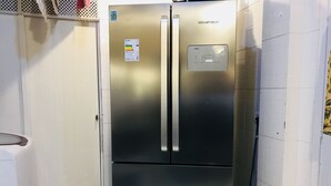A stainless steel refrigerator with a digital display and energy efficiency label, located in a narrow kitchen with white tiled walls. - Jump in Bed Ipanema 10 - Loft (Rio de Janeiro)