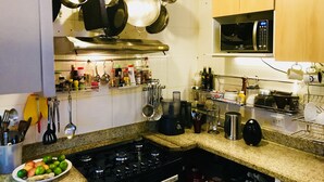 A kitchen with a stove, pots, and various utensils hanging on the wall. - Jump in Bed Ipanema 10 - Loft (Rio de Janeiro)