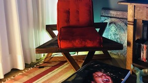 A room with a red chair, a surfboard, and a bookshelf. - Jump in Bed Ipanema 10 - Loft (Rio de Janeiro)