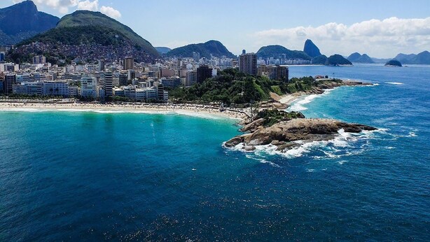 A coastal cityscape with a beach, buildings, and mountains. - Jump in Bed Ipanema 10 - Loft (Rio de Janeiro)