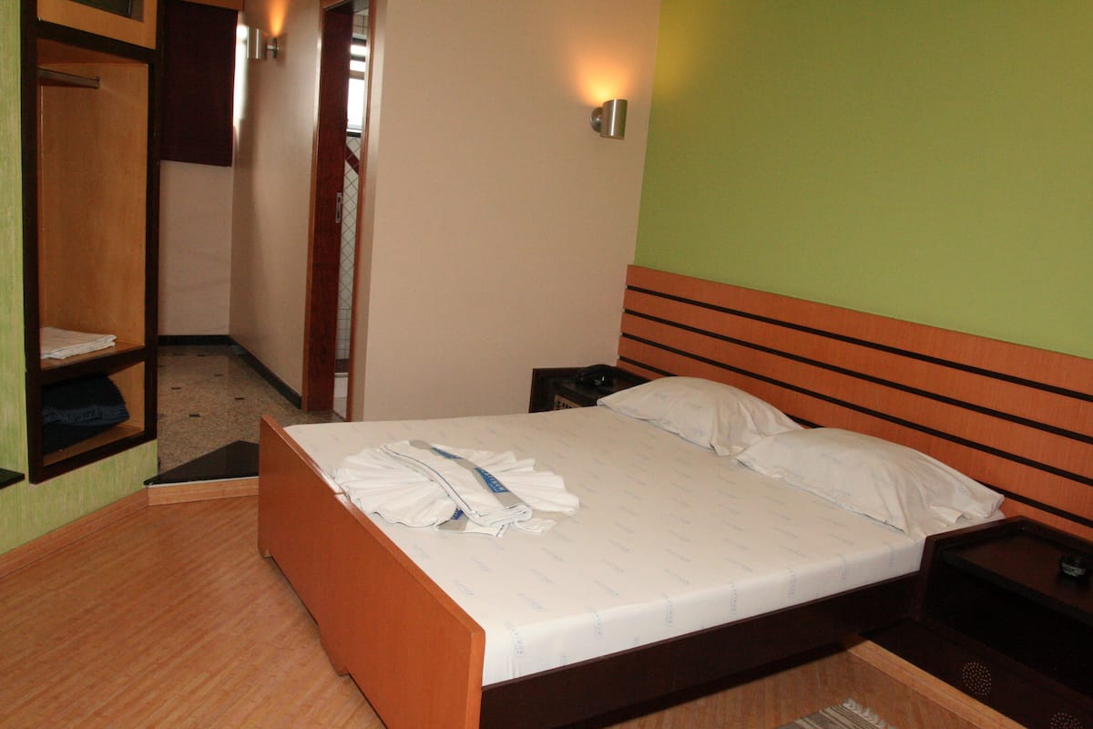 Ein Hotelzimmer mit einem hölzernen Bett, einem Nachttisch, einer Wandleuchte und einem Holzschrank.