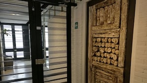Una habitación con una verja de metal negro, un muro de ladrillo blanco y una puerta de madera con troncos.