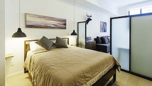 Un dormitorio con cama, lámparas de noche, un cuadro, una decoración de cabeza de ciervo y una puerta corredera.