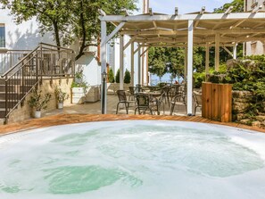 Un área de hidromasaje con una pérgola, asientos exteriores y vista al mar.