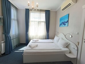 A hotel room with a double bed, a bedside table, a wall-mounted lamp, a painting, and a window with curtains. - Hotel Belle Epoque Beach (Varna)
