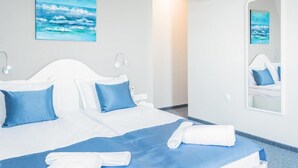 Una habitación de hotel con cama, espejo y un cuadro del océano.