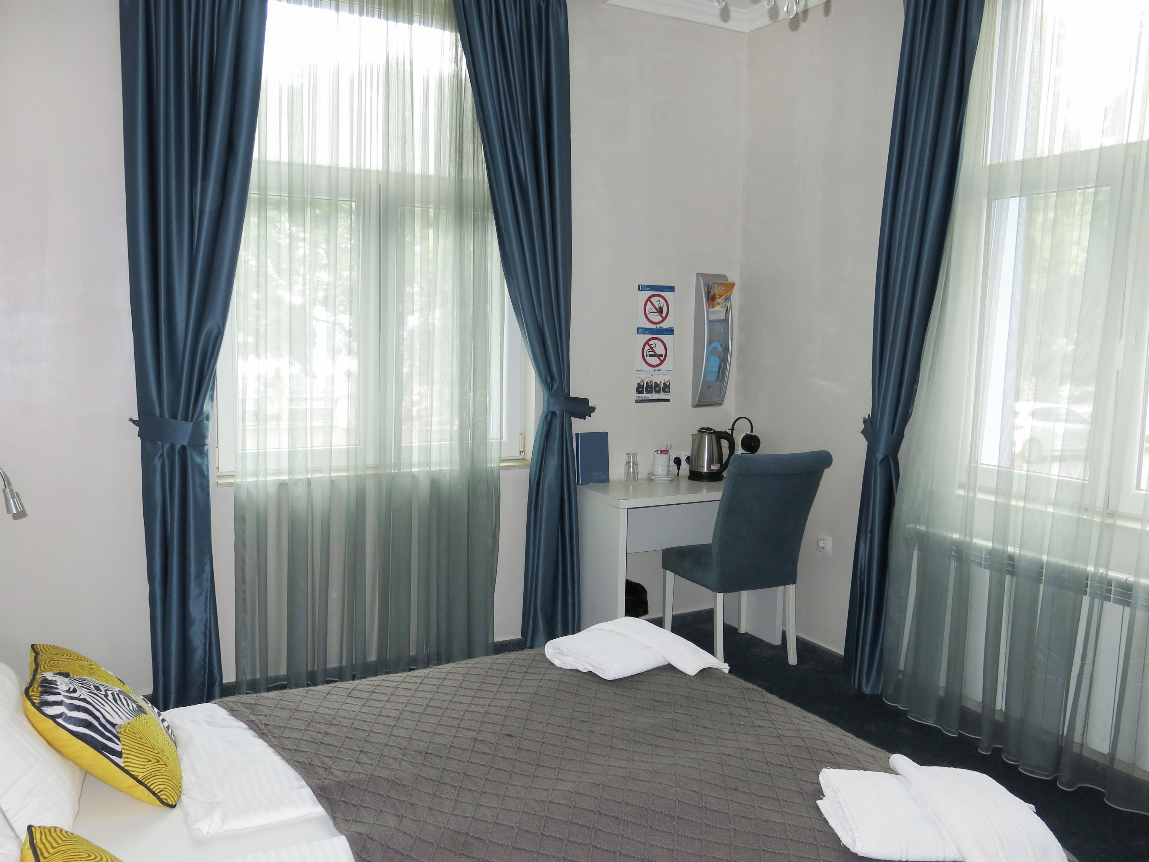 Une chambre d’hôtel avec un lit, un bureau, une chaise et une fenêtre avec des rideaux.