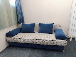 Un sofá con funda estampada y cojines a juego, ubicado frente a una pared con radiador.