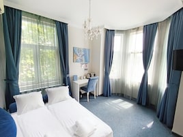 Habitación de hotel con cama, escritorio, silla y candelabro.